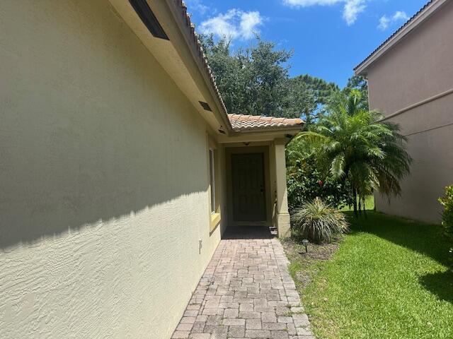 property entrance featuring stucco siding, a lawn, and a tile roof