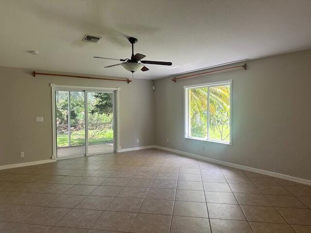 tiled spare room with healthy amount of natural light, a ceiling fan, and baseboards