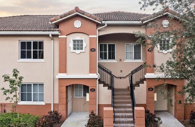 multi unit property with stairway, stucco siding, and a tiled roof