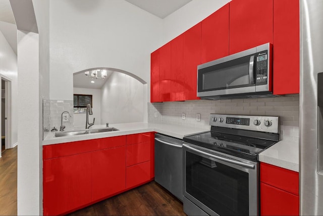 kitchen with appliances with stainless steel finishes, red cabinets, a sink, and dark wood finished floors