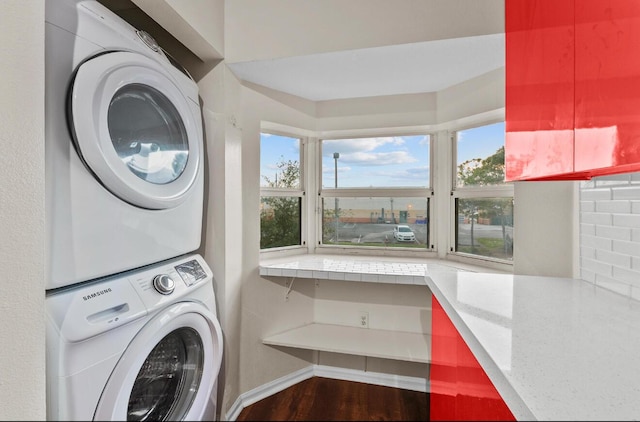 clothes washing area with estacked washer and dryer and wood finished floors