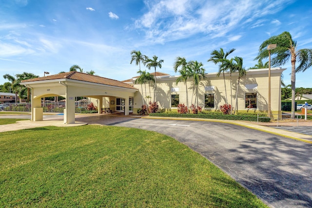 mediterranean / spanish house featuring driveway, a front lawn, stucco siding, and a carport