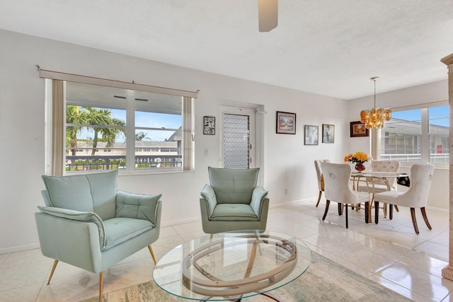 living area featuring a chandelier, baseboards, and ceiling fan