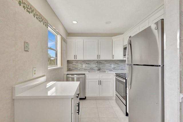 kitchen with stainless steel appliances, a sink, white cabinets, light tile patterned flooring, and light countertops