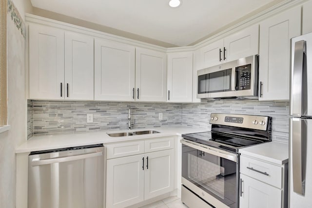kitchen with stainless steel appliances, a sink, light countertops, white cabinets, and backsplash