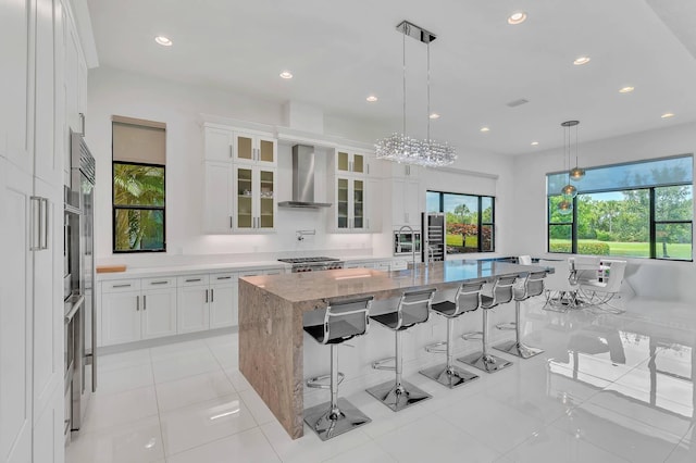 9219 Grand Prix Ln, Boynton Beach, FL 33472 - kitchen with wall chimney range hood, white cabinetry, recessed lighting, a breakfast bar, and light stone counters