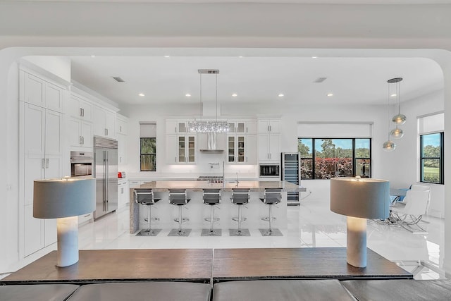 9219 Grand Prix Ln, Boynton Beach, FL 33472 - kitchen featuring built in appliances, white cabinets, plenty of natural light, a breakfast bar area, and recessed lighting