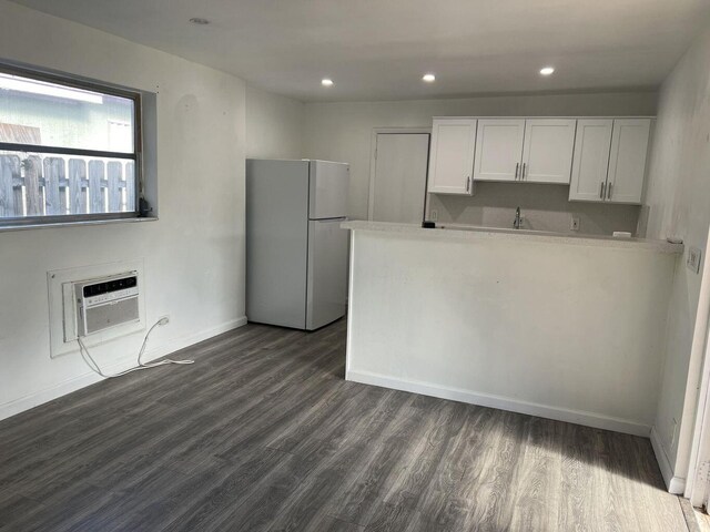 132 E Central Blvd, Lantana, FL 33462 - kitchen featuring freestanding refrigerator, dark wood-type flooring, light countertops, white cabinetry, and an AC wall unit