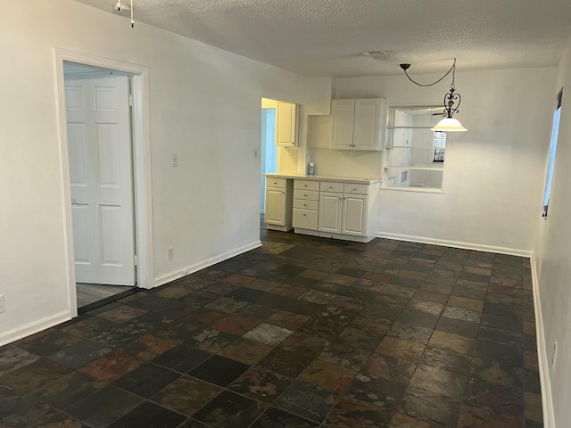 132 E Central Blvd, Lantana, FL 33462 - kitchen featuring a textured ceiling, light countertops, decorative light fixtures, baseboards, and white cabinets