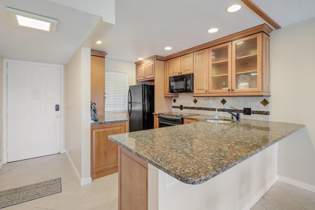 4411 Trevi Ct Unit 303, Lake Worth, FL 33467 - kitchen featuring black appliances, a sink, dark stone counters, baseboards, and a peninsula