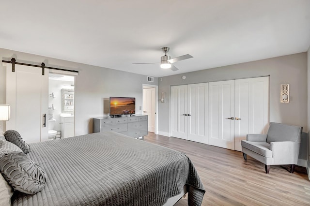1044 Cambridge C Unit 1044, Deerfield Beach, FL 33442 - bedroom featuring a barn door, light wood-style flooring, a ceiling fan, baseboards, and connected bathroom