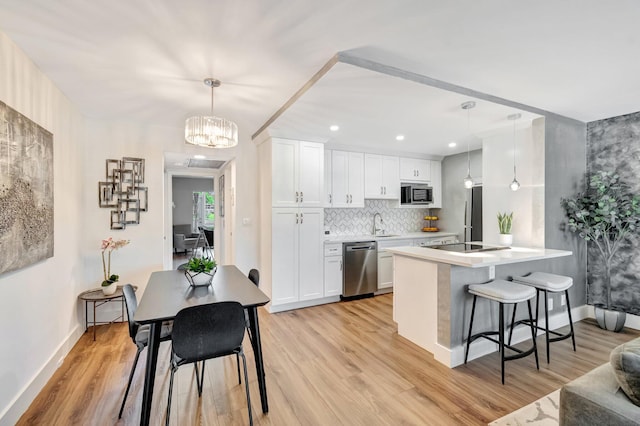 1044 Cambridge C Unit 1044, Deerfield Beach, FL 33442 - kitchen featuring dishwasher, a chandelier, a breakfast bar area, light wood-style floors, and baseboards