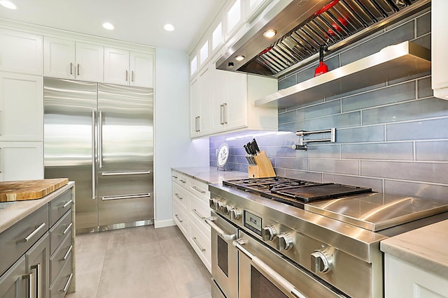 311 SE 11th St, Pompano Beach, FL 33060 - kitchen featuring high quality appliances, wall chimney range hood, white cabinetry, backsplash, and light stone counters