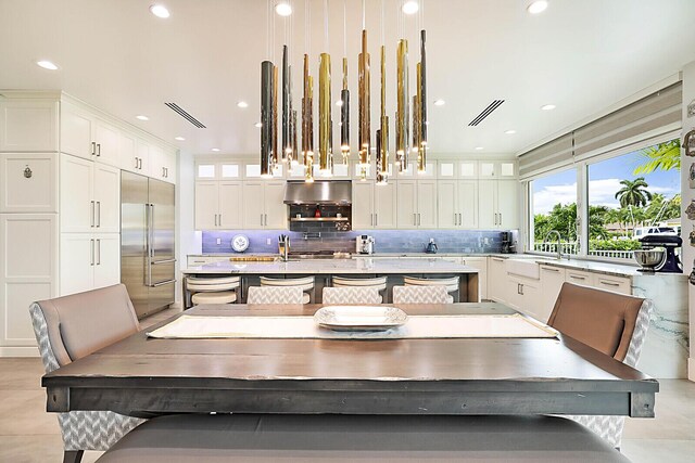 311 SE 11th St, Pompano Beach, FL 33060 - kitchen with built in refrigerator, a sink, a center island with sink, decorative backsplash, and white cabinets