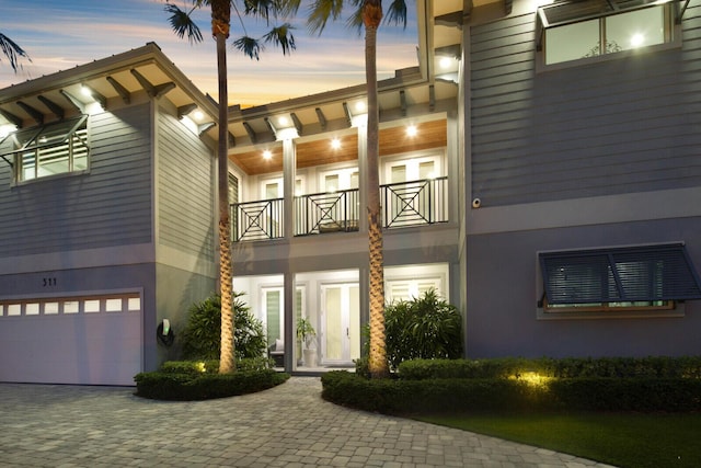 311 SE 11th St, Pompano Beach, FL 33060 - exterior entry at dusk with a balcony, an attached garage, driveway, and stucco siding