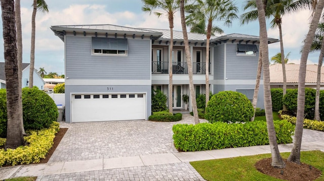 311 SE 11th St, Pompano Beach, FL 33060 - view of front of home with a balcony, a standing seam roof, decorative driveway, an attached garage, and metal roof