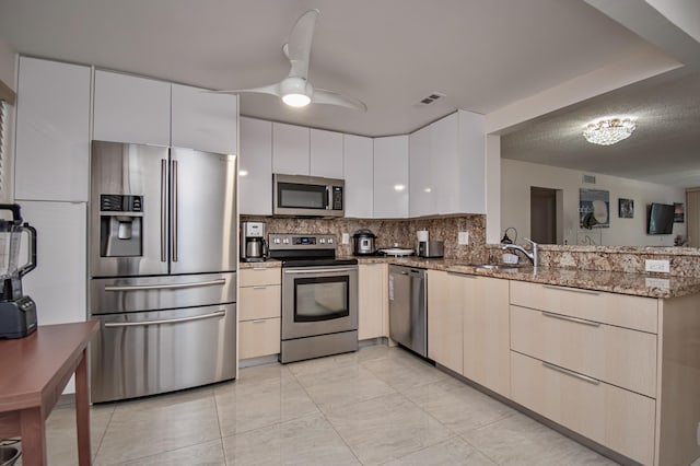 2301 Lucaya Ln Unit M3, Coconut Creek, FL 33066 - kitchen featuring appliances with stainless steel finishes, a sink, a peninsula, light stone counters, and decorative backsplash