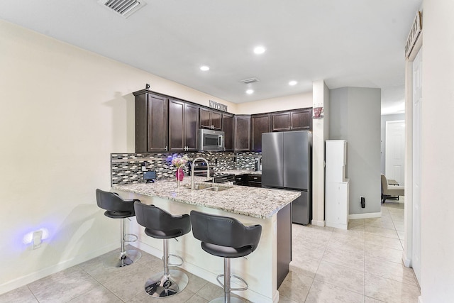 4080 Devenshire Ct, Coconut Creek, FL 33073 - kitchen featuring stainless steel appliances, a peninsula, dark brown cabinets, baseboards, and tasteful backsplash
