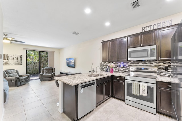 4080 Devenshire Ct, Coconut Creek, FL 33073 - kitchen featuring stainless steel appliances, a sink, open floor plan, dark brown cabinets, and backsplash