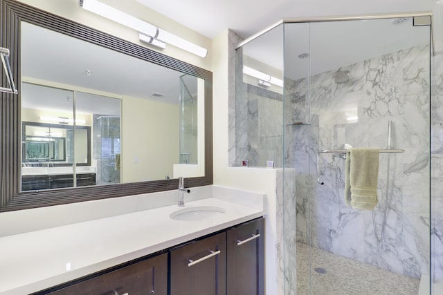 bathroom featuring a marble finish shower and vanity