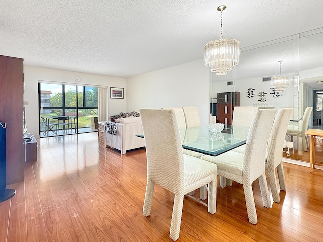 4960 E Sabal Palm Blvd Unit 206, Tamarac, FL 33319 - dining area with light wood-type flooring, a chandelier, and a textured ceiling