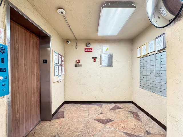 4960 E Sabal Palm Blvd Unit 206, Tamarac, FL 33319 - hall with elevator, a textured wall, baseboards, mail area, and stone finish flooring