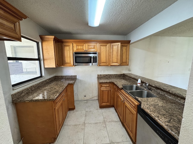 1453 Lake Crystal Dr Unit H, West Palm Beach, FL 33411 - kitchen with stainless steel appliances, a sink, brown cabinetry, a textured ceiling, and dark stone counters