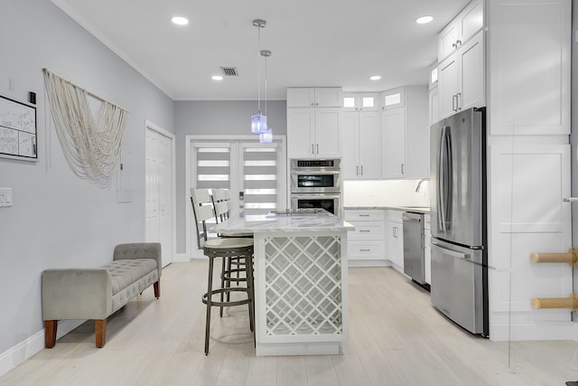 1511 S Palmway, Lake Worth Beach, FL 33460 - kitchen featuring appliances with stainless steel finishes, white cabinetry, a breakfast bar area, light wood-style flooring, and a center island