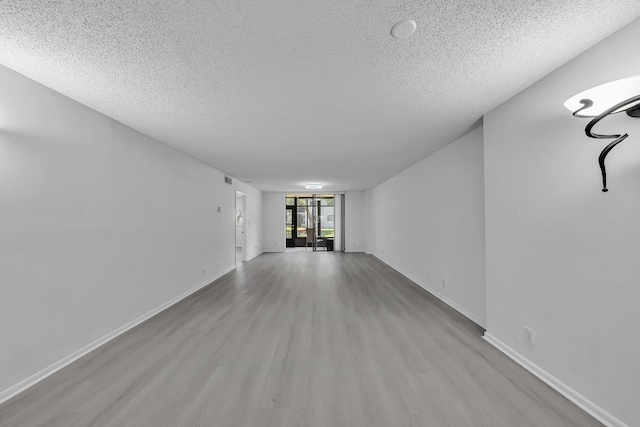 15244 Lakes Of Delray Blvd Unit 112, Delray Beach, FL 33484 - unfurnished living room with a textured ceiling, wood finished floors, and baseboards