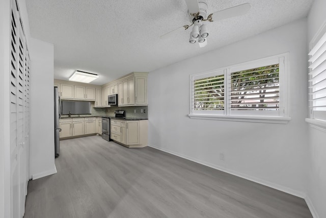 15244 Lakes Of Delray Blvd Unit 112, Delray Beach, FL 33484 - kitchen with stainless steel appliances, cream cabinetry, light wood-style floors, a textured ceiling, and a ceiling fan