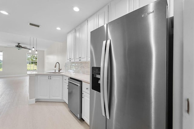 122 Ashley Ct, Jupiter, FL 33458 - kitchen with appliances with stainless steel finishes, a sink, light wood-type flooring, white cabinets, and ceiling fan