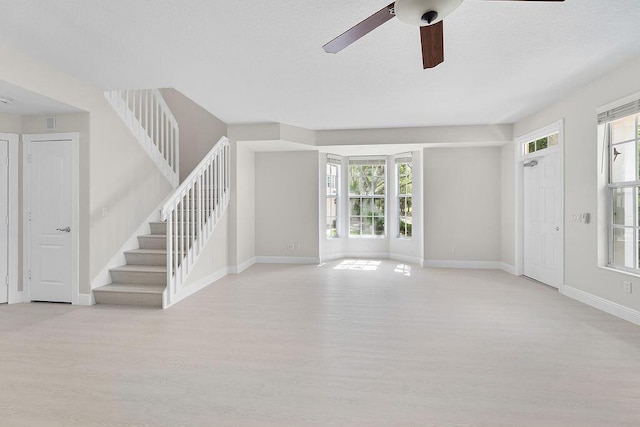 122 Ashley Ct, Jupiter, FL 33458 - unfurnished living room featuring light wood-type flooring, stairs, plenty of natural light, and a textured ceiling