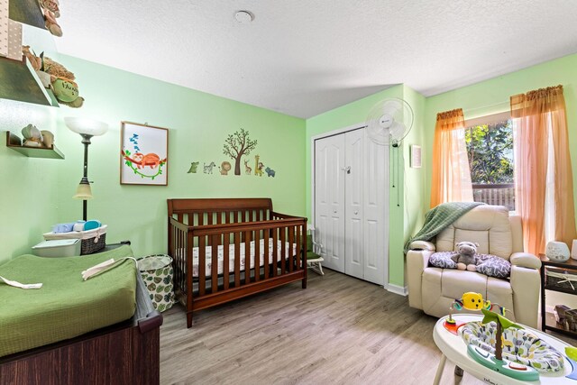 2389 SW Caballero St, Port Saint Lucie, FL 34953 - bedroom with wood finished floors, a closet, a textured ceiling, and a nursery area