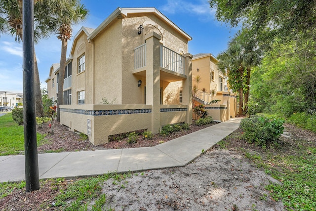 1673 SE Green Acres Cir Unit Nn-202, Port Saint Lucie, FL 34952 - view of side of home featuring a balcony, stucco siding, and a fenced front yard