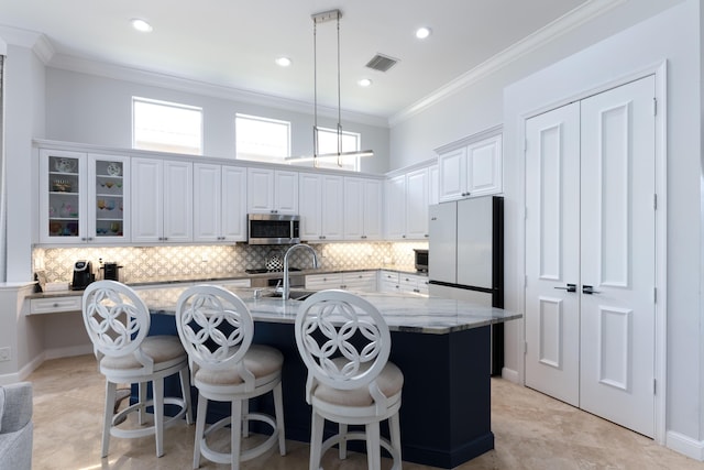 157 Esperanza Way, Palm Beach Gardens, FL 33418 - kitchen with stainless steel microwave, freestanding refrigerator, ornamental molding, plenty of natural light, and white cabinets