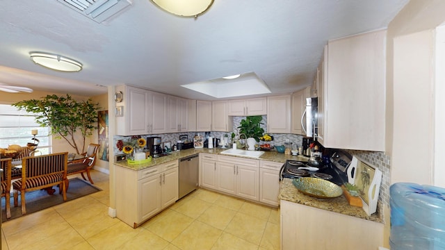 kitchen with appliances with stainless steel finishes, decorative backsplash, a sink, and light tile patterned floors