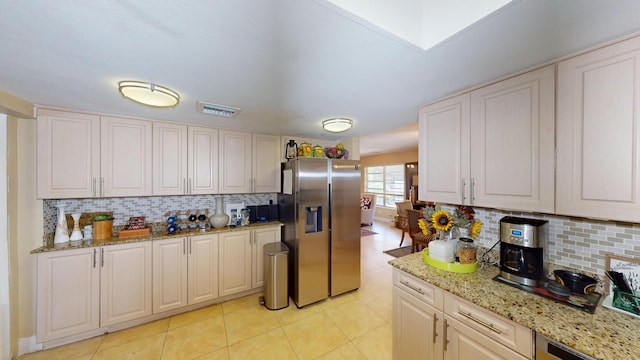 kitchen with stainless steel fridge, light tile patterned floors, tasteful backsplash, and light stone counters