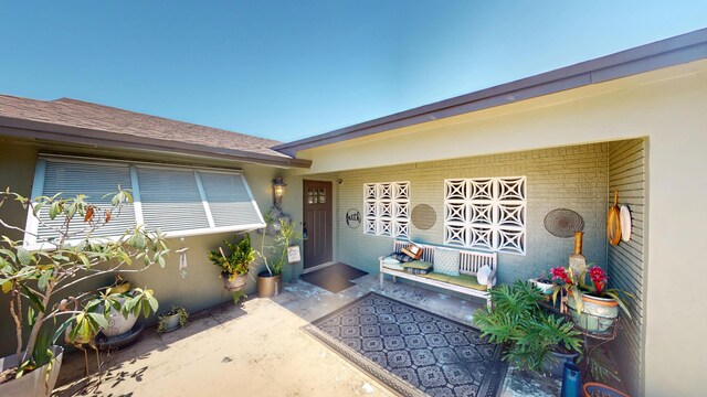 view of exterior entry with stucco siding and a porch