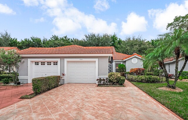 7043 Summer Tree Dr, Boynton Beach, FL 33437 - mediterranean / spanish house with an attached garage, concrete driveway, a tile roof, and stucco siding