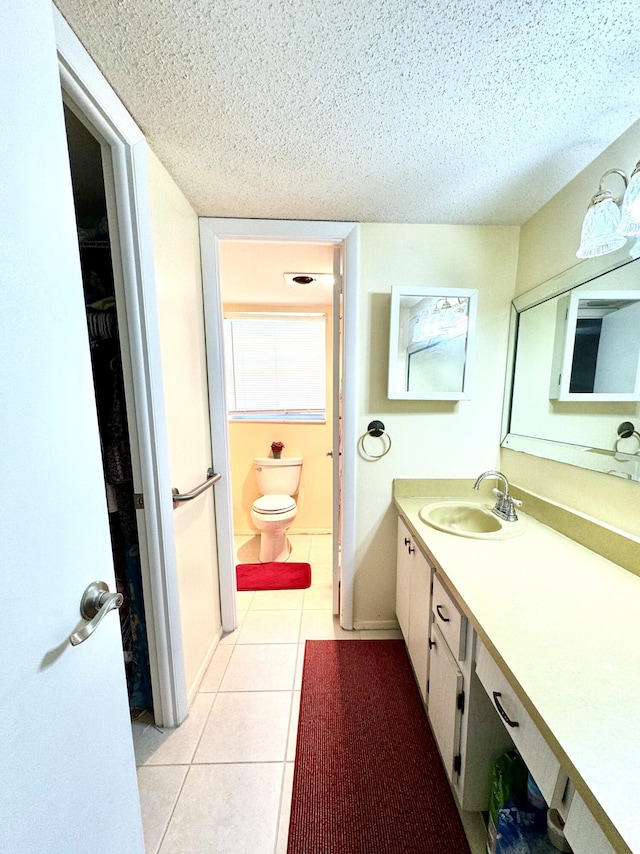 full bath featuring tile patterned flooring, toilet, vanity, a textured ceiling, and a spacious closet