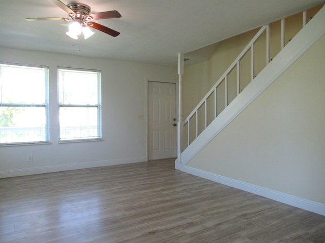 5310 Palm Dr, Fort Pierce, FL 34982 - empty room with stairs, wood finished floors, a ceiling fan, and baseboards