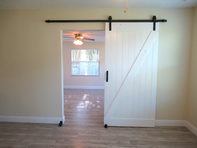 5310 Palm Dr, Fort Pierce, FL 34982 - unfurnished room with a barn door, wood finished floors, a ceiling fan, and baseboards