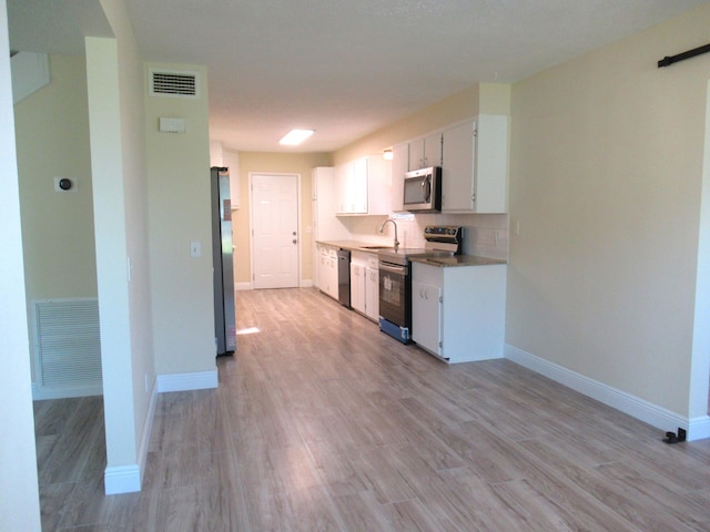 5310 Palm Dr, Fort Pierce, FL 34982 - kitchen with stainless steel appliances, a sink, white cabinets, light wood finished floors, and baseboards