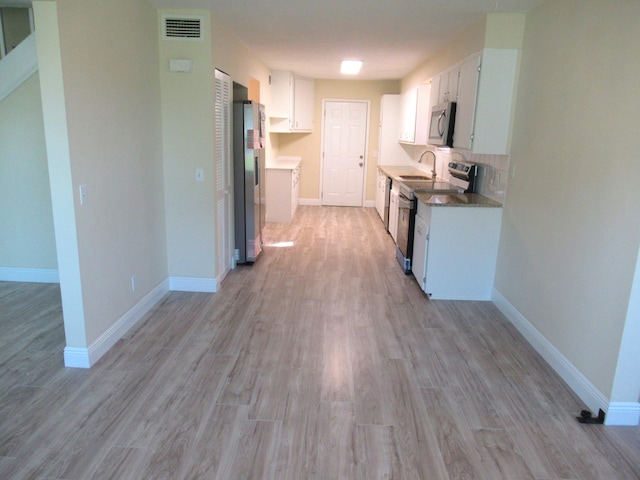 5310 Palm Dr, Fort Pierce, FL 34982 - kitchen with appliances with stainless steel finishes, light wood-style floors, white cabinets, and backsplash