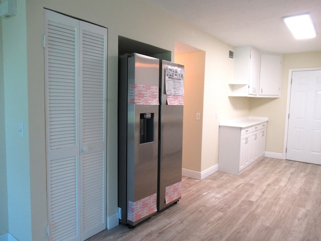 5310 Palm Dr, Fort Pierce, FL 34982 - kitchen featuring stainless steel fridge, light wood-style floors, white cabinets, baseboards, and light countertops