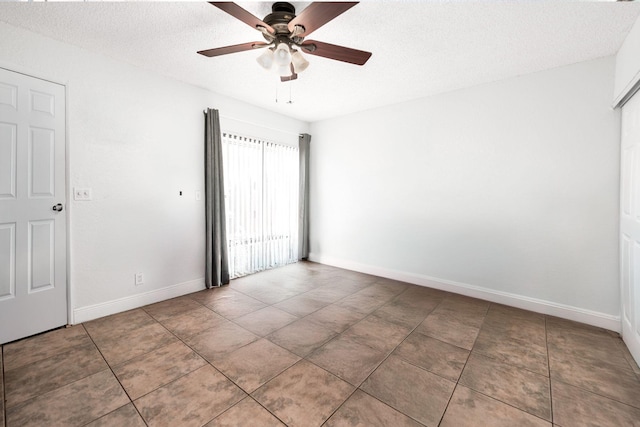 tiled spare room with ceiling fan, a textured ceiling, and baseboards