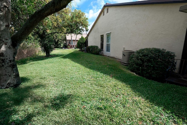 view of green lawn featuring central AC
