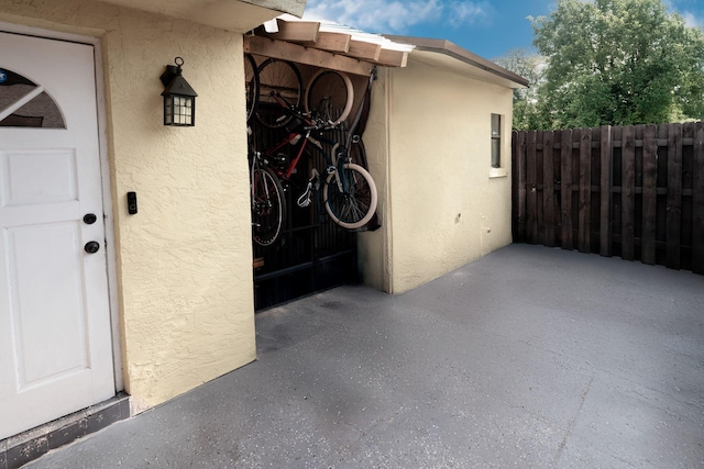 entrance to property featuring stucco siding and fence