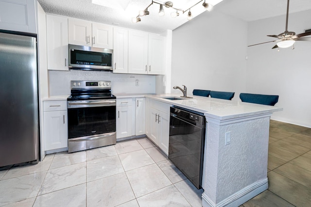kitchen featuring appliances with stainless steel finishes, a sink, a peninsula, and white cabinets