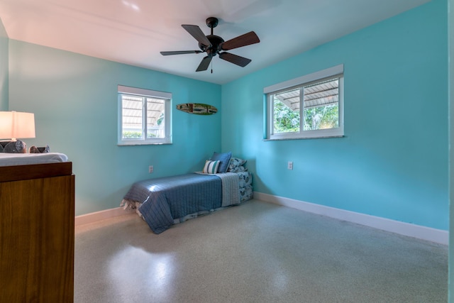 bedroom with multiple windows, baseboards, ceiling fan, and speckled floor
